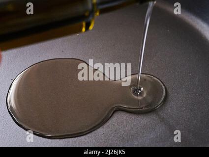 Berlin, Deutschland. 30. März 2022. ILUUSTRATION - Eine Frau gießt Sonnenblumenöl in eine Pfanne. Quelle: Annette Riedl/dpa/Alamy Live News Stockfoto