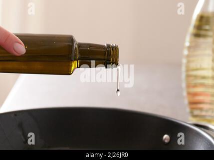 Berlin, Deutschland. 30. März 2022. ILUUSTRATION - Eine Frau gießt Sonnenblumenöl in eine Pfanne. Quelle: Annette Riedl/dpa/Alamy Live News Stockfoto