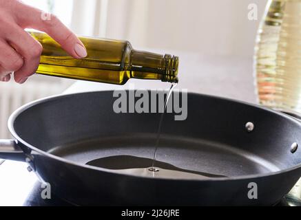 Berlin, Deutschland. 30. März 2022. ILUUSTRATION - Eine Frau gießt Sonnenblumenöl in eine Pfanne. Quelle: Annette Riedl/dpa/Alamy Live News Stockfoto