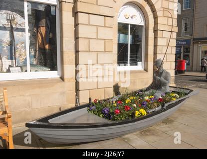 Eine Skulptur einer Person, die in einem Ruderboot vor dem River Tweed Museum of Lachs Fishing in Kelso Town Hall, Scottish Borders, Schottland, angeln kann. Stockfoto