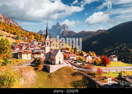 Drohnenflug über die katholische Kirche von San Lorenzo im Dorf Selva di Cadore. Schöne kleine Stadt im Herbst Dolomiten Berge. Dolomiten, Pr Stockfoto