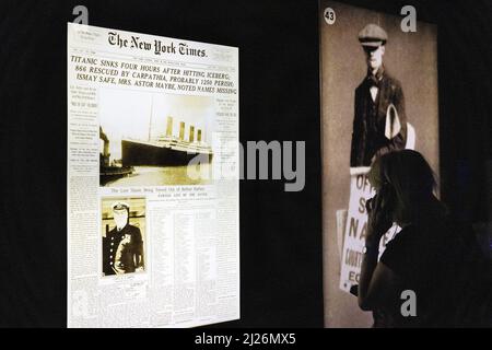 Die Titanic-Ausstellung; ein Besucher, der sich die Schlagzeilen der Zeit nach dem Untergang der RMS Titanic im Jahr 1912 ansieht; London, Großbritannien Stockfoto