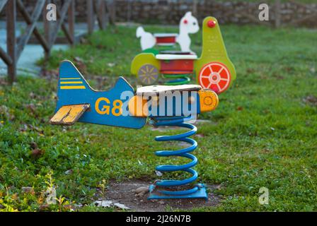 Wippe Schaukel in Form eines hölzernen Flugzeug mit einer Quelle in einem Kinder ist Spielplatz bei Sonnenuntergang Stockfoto