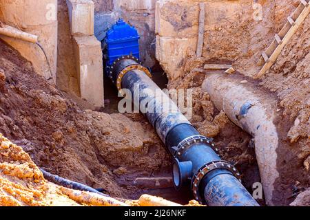 Installation der Verteilungseinheit des Heiz- und Wasserversorgungsnetzes. Rahmen für die Verbindung von Rohren im Erdgraben. Stockfoto