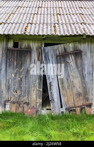 Schiefe Türen auf einer alten Holzscheune Stockfoto
