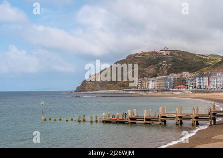 Blick auf die Aberystwyth Cliff Railway über Gebäude am Meer und einen kleinen hölzernen Steg. Straßenbahnen sind auf der Constitution Hill-Strecke zu sehen. Stockfoto