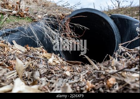 HDPE-Drainage unter einer Straßeneinfahrt. Das Rohr dient zur Förderung von Regenwasser zwischen Gräben. Stockfoto