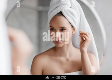 Tägliche Hygieneroutine. Junge Frau putzt Ohren mit Wattestäbchen, während sie morgens im Badezimmer Schönheitsbehandlungen macht Stockfoto