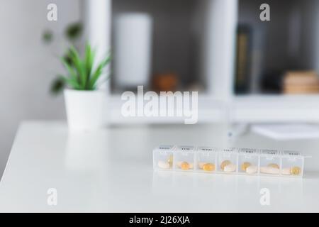 Nahaufnahme der medizinischen Pille Box mit Dosen von Tabletten für den täglichen Nehmen Sie ein Medikament mit weißen, gelben Drogen und Kapseln zur Behandlung verwendet, die Krankheit zu heilen. Gesunder Lebensstil, Vitamine, Omega-3-Ergänzungen Stockfoto