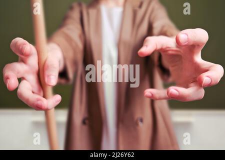 Die Lehrerin zieht ihre Hände nach vorne und will sich im Klassenzimmer an die Schultafel greifen Stockfoto