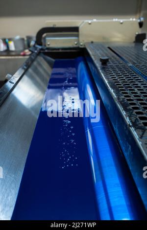 Farbe und glänzende Walzen von Offset-Druckmaschine. Offset-Farbe. Cyanblau. Vertikal aufgenommene Fotos, Vorderseite des Fotos mit ausgewähltem Fokus Stockfoto