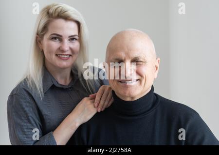 Erwachsen liebevoll aufmerksame fürsorgliche Enkelin umarmt ältere 75s Großvater. Junge Erwachsene Tochter umarmt gealterten Vater aus der Ferne in gemütlich Stockfoto