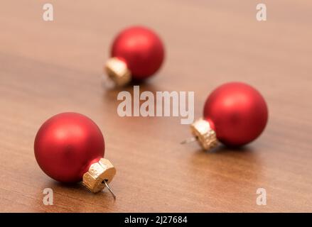 Ein Foto von drei roten weihnachtskugeln auf einem Holzhintergrund Stockfoto