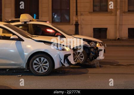 Beschädigte weiße Autos auf der Straße nach einem Unfall mit beschädigten Stoßfängern. Fahrlässiges Fahren Stockfoto