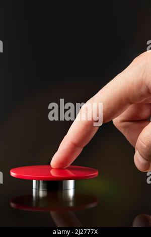 Die Hand eines Mannes drückt einen großen roten Knopf. Rote Taste auf dunklem Hintergrund. Die Drohung mit nuklearen oder chemischen Massenvernichtungswaffen. Rakete Stockfoto