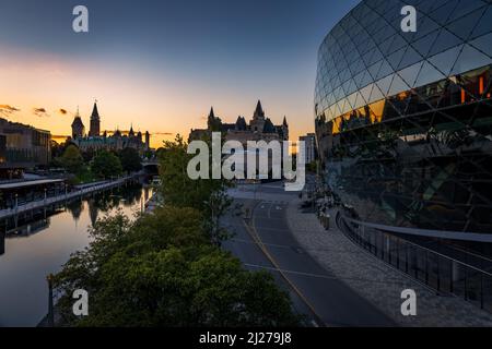 Das Ottawa Convention Center, bei Sonnenuntergang, mit dem Parlament und dem Rideau-Kanal im Hintergrund Stockfoto