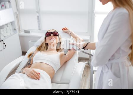 Lächelnde Frau, die im Schönheitssalon eine Laserepilation erhält Stockfoto