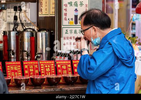 Hongkong. 30. März 2022. Ein Mann konsumiert medizinischen Kräutertee in einem Geschäft in North Point. Die Regierung Hongkongs hat sich aktiv für die Verwendung traditioneller chinesischer Medizin zur Behandlung von COVID-19 eingesetzt. Experten sind jedoch besorgt, dass es nicht genügend Beweise aus kontrollierten, von Experten überprüften Studien über die Wirksamkeit dieser Behandlungen für das neuartige Coronavirus gibt. (Bild: © Ben Marans/SOPA Images via ZUMA Press Wire) Stockfoto