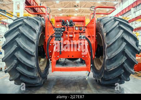 Großer roter Erntemaschinen oder Traktor, der gerade in der Produktion für die Herstellung von Landmaschinen auf Produktionslinie in der Fabrik montiert wird. Stockfoto