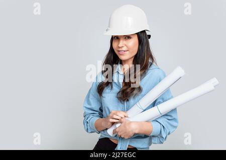 Junge attraktive Architektin mit weißem Helm und architektonischen Plänen Stockfoto