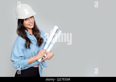 Junge attraktive Architektin mit weißem Helm und architektonischen Plänen Stockfoto