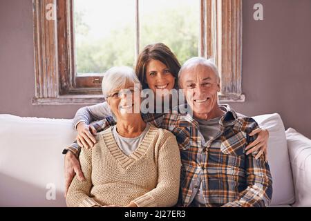 Ich liebe meine Eltern. Ein beschnittenes Porträt eines glücklichen älteren Ehepaares und ihrer erwachsenen Tochter zu Hause. Stockfoto
