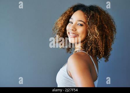 Shes happy-go-Lucky. Studioaufnahme einer attraktiven jungen Frau vor grauem Hintergrund. Stockfoto