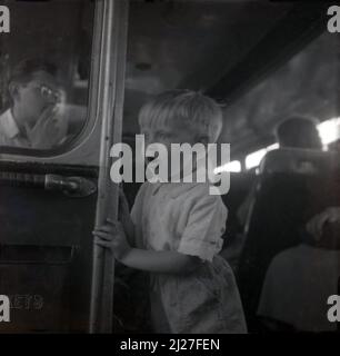 1955, historischer, aufgeregt kleiner Junge, der sich auf einer Stahlpfosten hält, während er in einem nordwestlichen Bus, Stockport, Manchester, England, Großbritannien, reist. Die 1923 gegründete North Western Road Car Company in Stockport war in dieser Zeit ein großes Transportunternehmen in der Region mit über 500 Bussen. Stockfoto