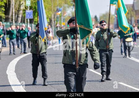 20/04/2014, Belfast, Nordirland. Die farbige Partei der Irischen Republikanischen Sozialistischen Partei (IRSP), dem politischen Flügel der ehemaligen Irischen Nationalen Befreiungsarmee (INLA), macht sich während der Osterfeier für ihre toten Kameraden in paramilitärischen Uniformen auf den Weg durch den Milltown-Friedhof Stockfoto