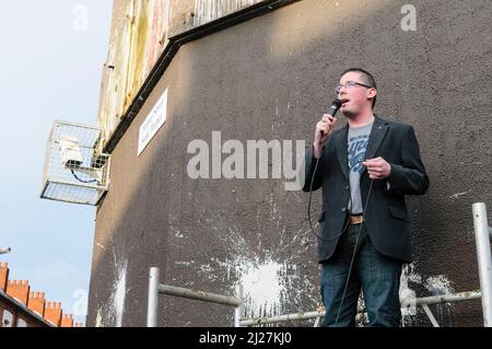 31/08/2009, Belfast, Nordirland. Niall O'Donnghaile, Repräsentant von Sinn Fein in East Belfast, spricht bei einer Kundgebung an die Menge, um die Schließung des Mountpottinger PSNI-Bahnhofs zu feiern. Auf die Kundgebung folgte eine Nacht konfessioneller Aufstände und Unruhen. Stockfoto