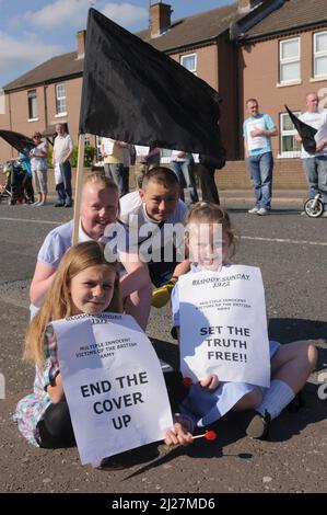 14/06/2010, Short Strand, Belfast, Nordirland. Kinder halten Protestplakate vor einem Protest mit schwarzer Flagge vor dem Saville Report on Bloody Sunday hoch Stockfoto