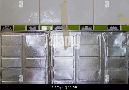 Das Aluminiumblech zum Schutz des Öls spritzt vor dem Kochen in der Nähe des Gasofens in der städtischen Küche, Vorderansicht mit dem Kopierraum. Stockfoto