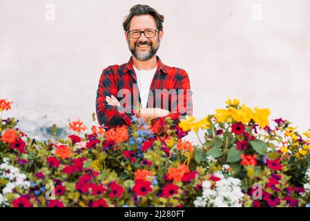 Portrait von glücklichen Mann Floristen lächelnd und posiert mit vielen Blüten bunten Blumen vor ihm. Weißer Hintergrund. Konzept des Store Business Flo Stockfoto