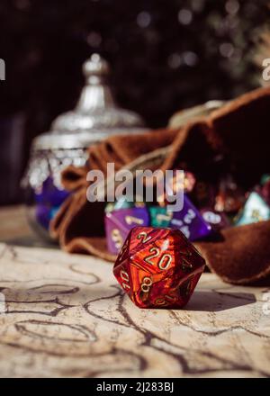 Vertikales Bild eines roten 20-seitigen Rollenspielwürfels im Hintergrund eines Würfelbeutels Stockfoto