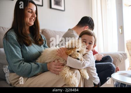 Das kleine Mädchen umarmte ihren Hund und genoss die Zeit mit ihrer Familie zu Hause. Stockfoto