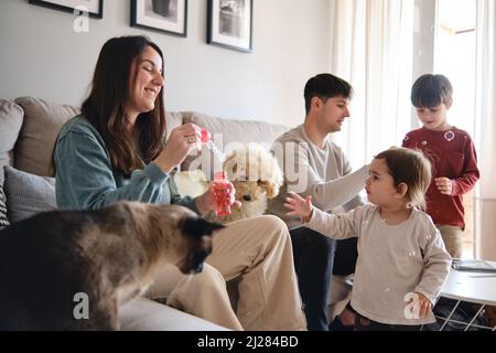 Glückliche Familie, die Spaß zusammen beim Spielen bläst Seifenblasen zu Hause. Stockfoto