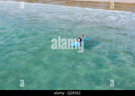 Drohnenansicht des asiatischen Surfbretters am Strand von Kata Beach, Phuket, Thailand, surft ein Mann. Stockfoto