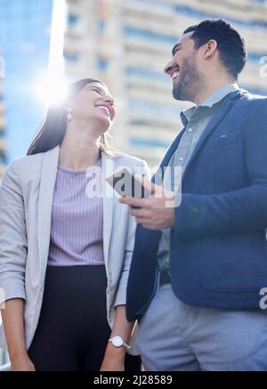 Ich bin froh, dass wir uns hier aufhalten konnten. Aufnahme von zwei jungen Geschäftsleuten, die zusammen ein Smartphone benutzen. Stockfoto