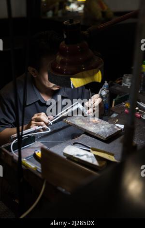 Thailändischer Juwelier, der in einer Werkstatt feinen Schmuck herstellt Stockfoto