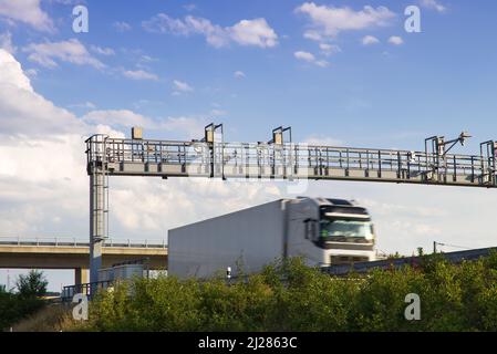 LKW fahren unter der Autobahnmautstelle, LKW in Bewegung. Transport auf gebührenpflichtiger Autobahn Stockfoto