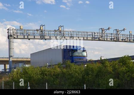 LKW fahren unter der Autobahnmautstelle, LKW in Bewegung. Transport auf gebührenpflichtiger Autobahn Stockfoto