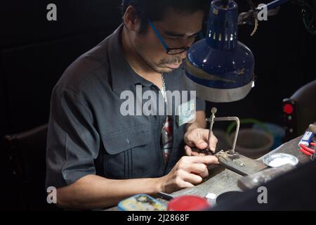 Thailändischer Juwelier, der in einer Werkstatt feinen Schmuck herstellt Stockfoto