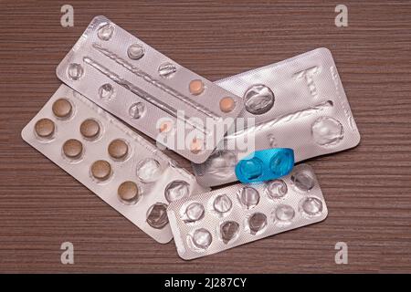 Stapel von gebrauchten medizinischen Blisterpackungen mit verschreibungspflichtigen Pillen auf Holzhintergrund Stockfoto