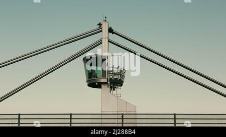 Minimalistischer Blick auf einen modernen Brückenturm und Hängeseile mit klaren Linien und modernem Industriedesign vor klarem Himmel. Stockfoto