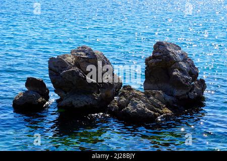 Riesige Felsen aus dem Meeresboden ragen über die Oberfläche des Meerwassers Stockfoto