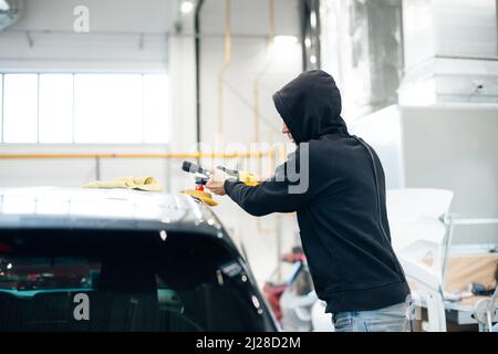 Professioneller Mechaniker, der ein Poliergerät zum Reinigen eines Autos von Kratzern verwendet. Stockfoto