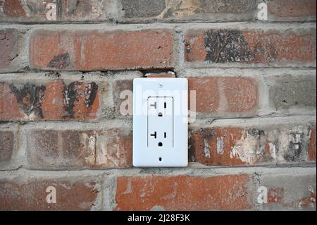Nahaufnahme einer Steckdose in einer Ziegelwand Stockfoto
