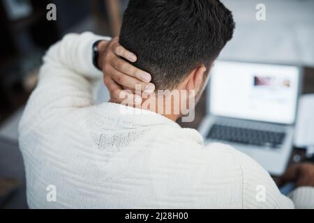 Je mehr Stress, desto weniger näher am Erfolg. Rückansicht eines jungen Mannes, der bei der Arbeit von zu Hause aus Nackenschmerzen hatte. Stockfoto