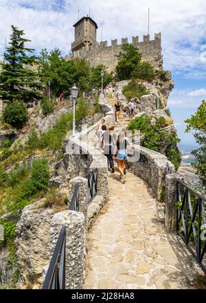 Eine vertikale Aufnahme von Touristen, die auf dem Pass of the Witches-Pfad zum Guaita-Turm hinaufsteigen Stockfoto