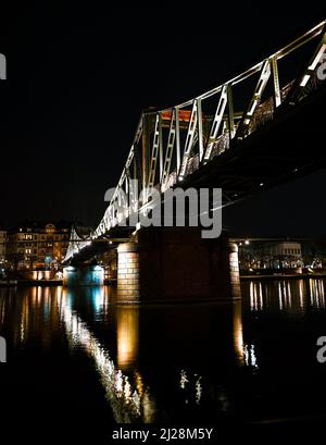 Die Eiserne Brücke („eiserner Steg“) in Frankfurt am Main leuchtet in der Nacht. Stockfoto